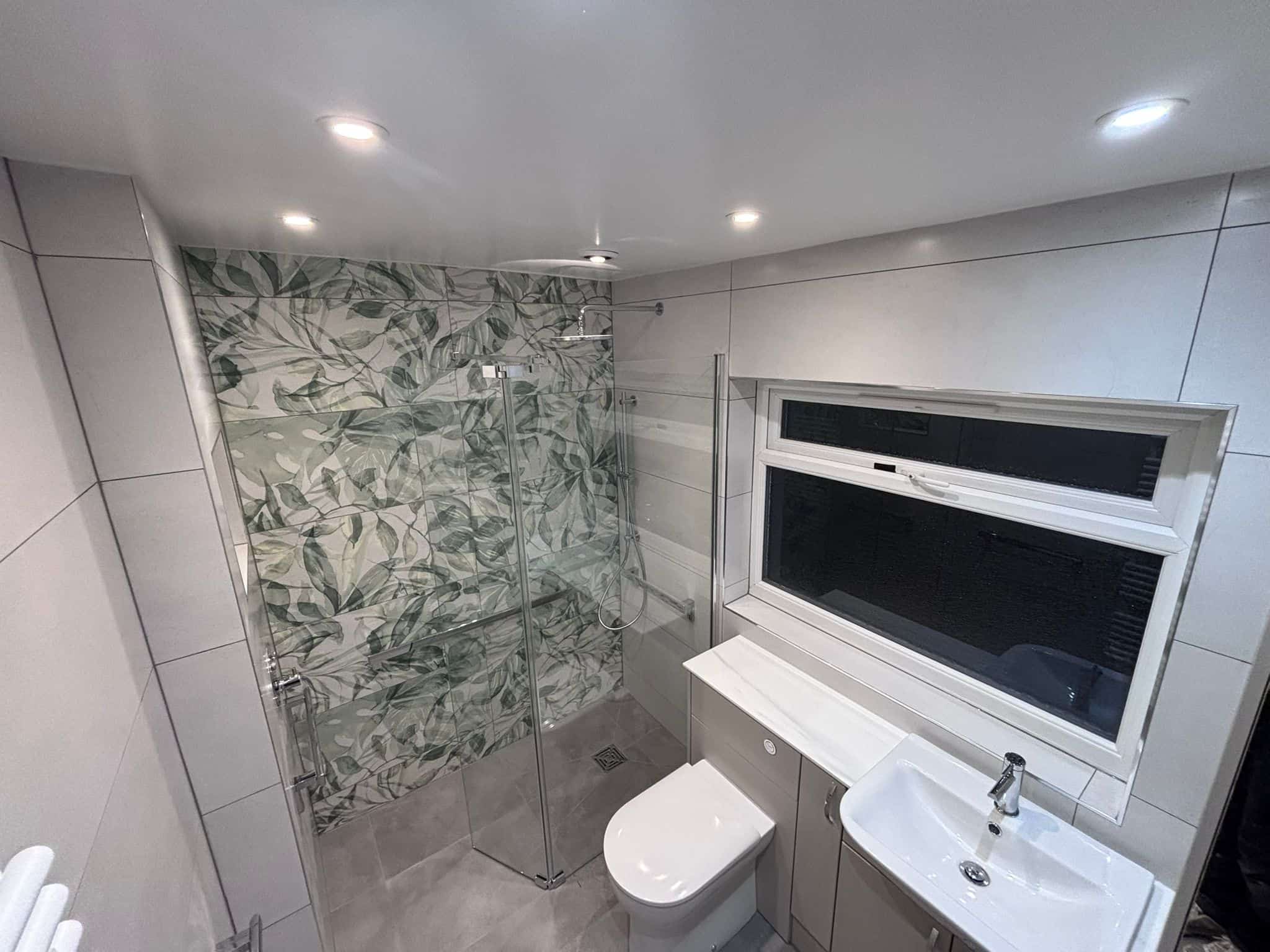 Level-access wet room with a glass screen, botanical feature tiles and grab rails