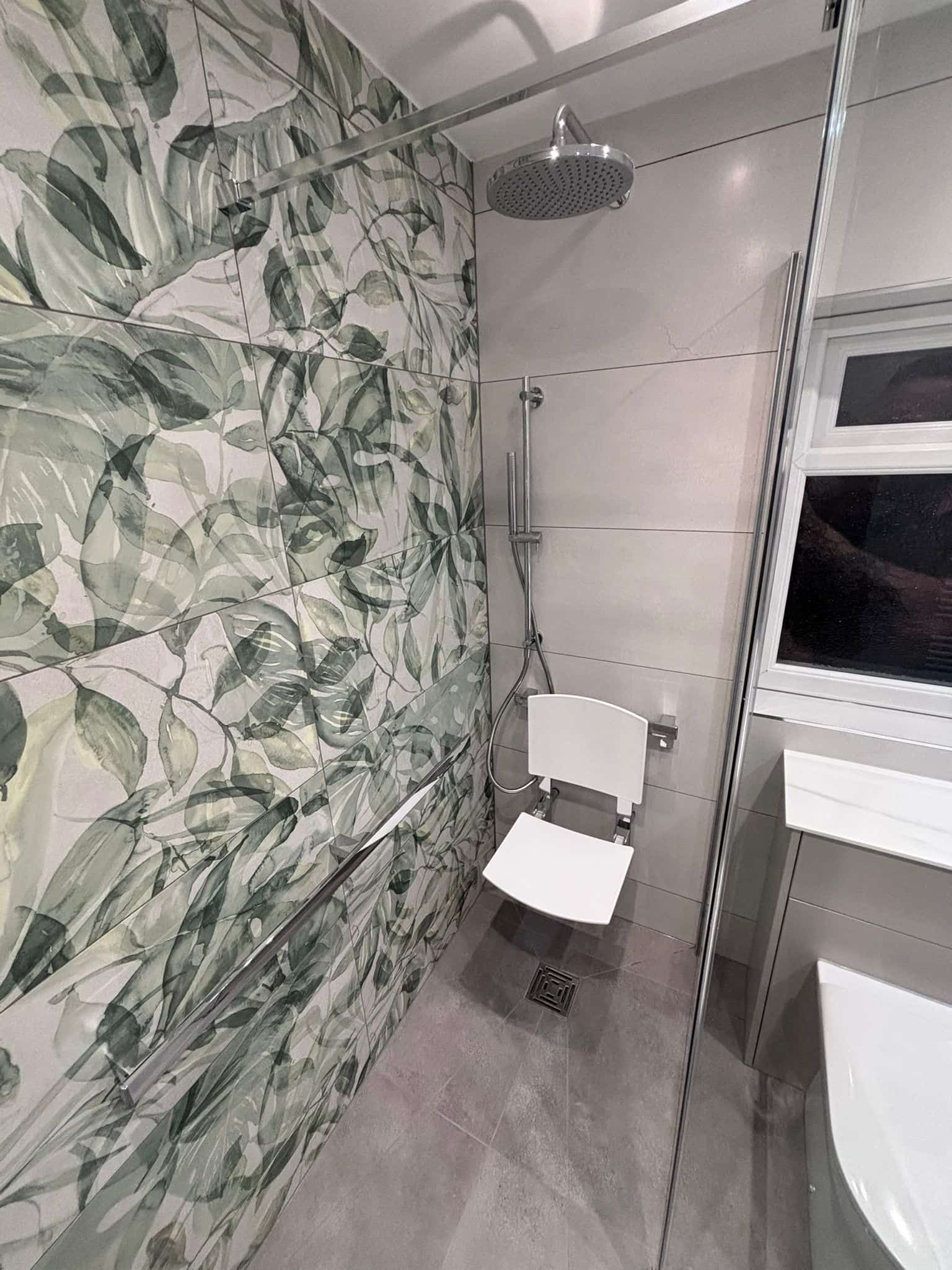 Accessible shower with a fold-down seat, grab rails and botanical feature tiling