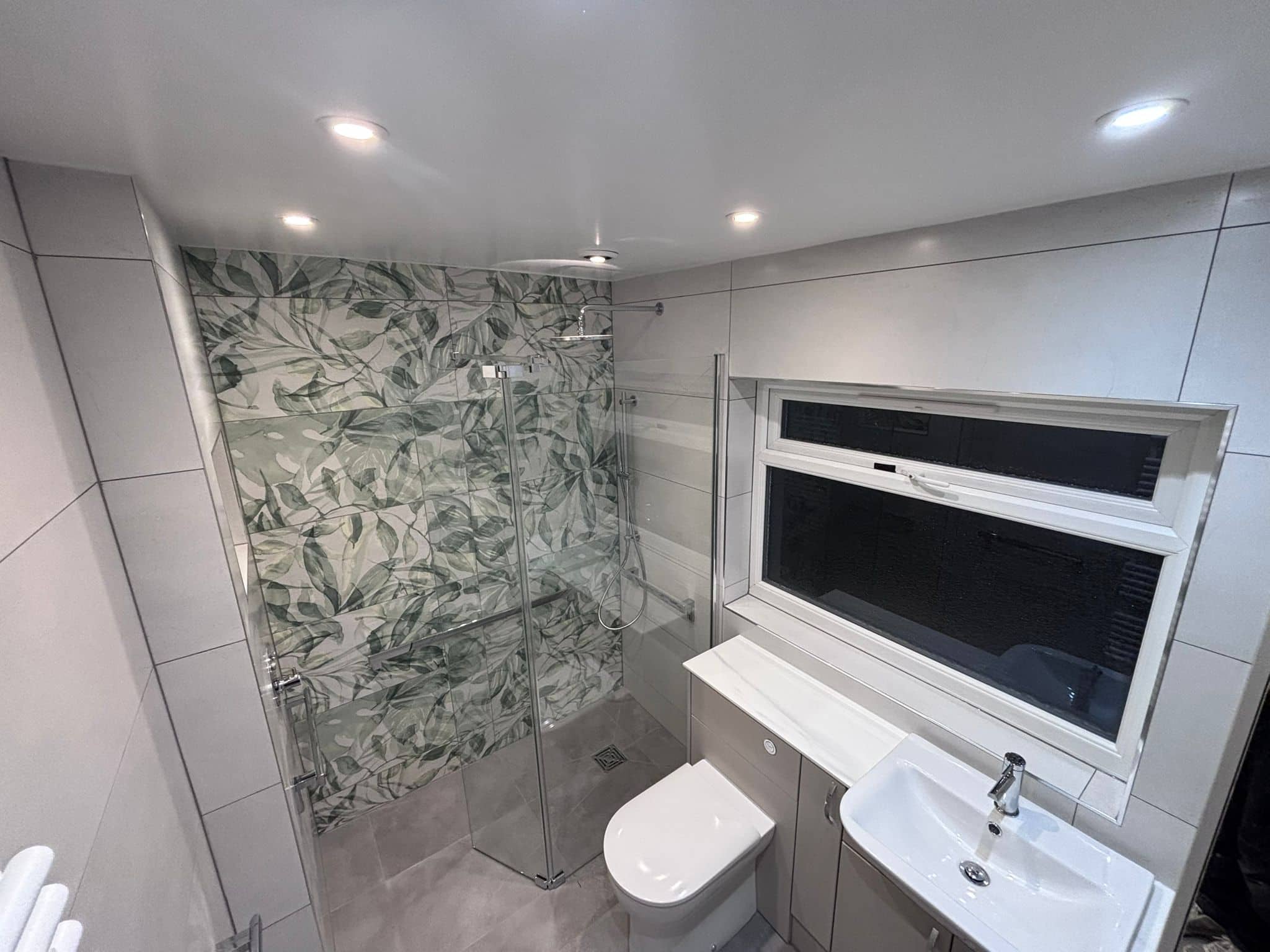 Level-access wet room with a glass screen, botanical feature tiles and grab rails