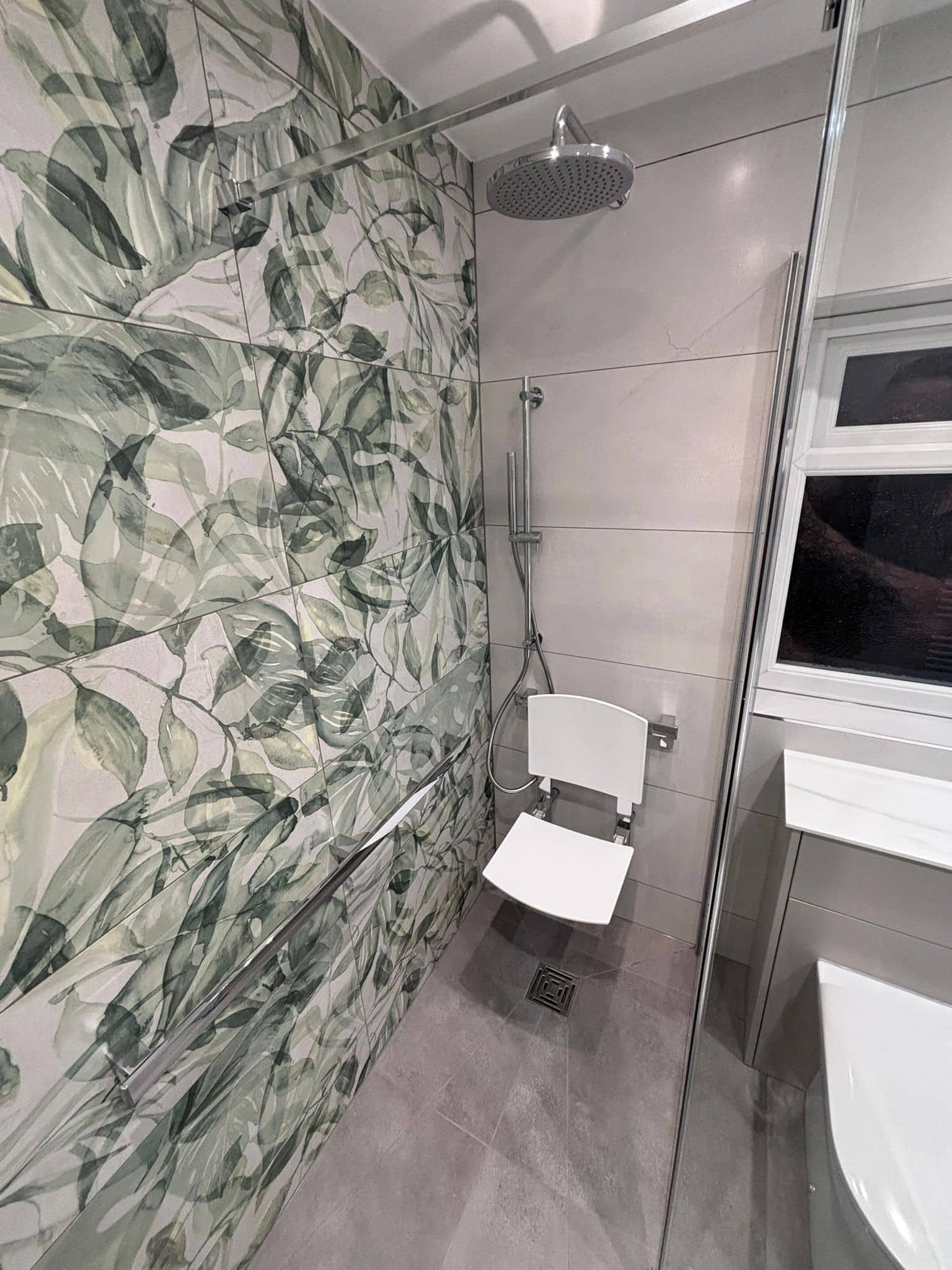 Accessible shower with a fold-down seat, grab rails and botanical feature tiling