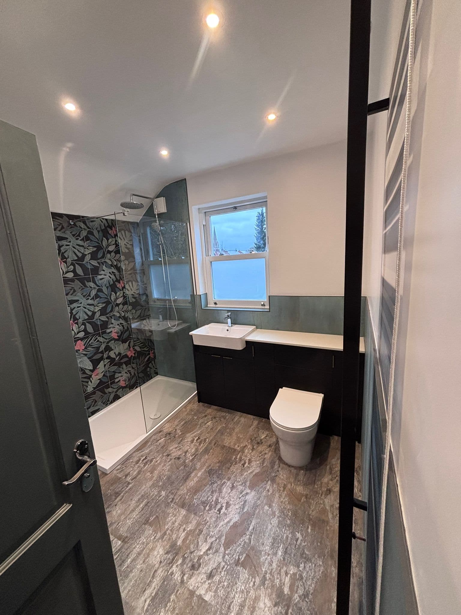 Loft en-suite with a tropical feature wall, walk-in glass shower and dark vanity