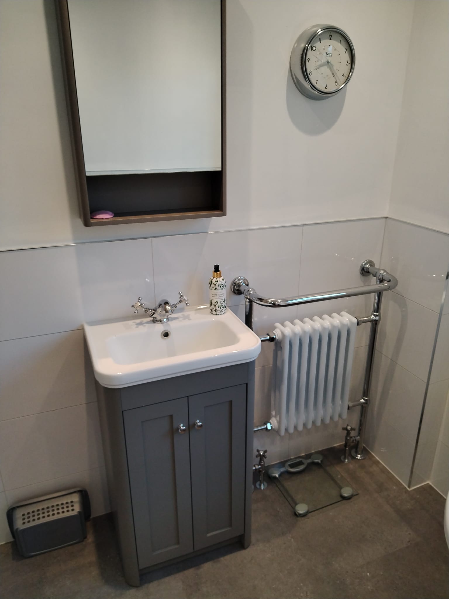 Grey shaker vanity unit with a white basin and chrome cross head taps, beside a traditional white column radiator with a towel rail