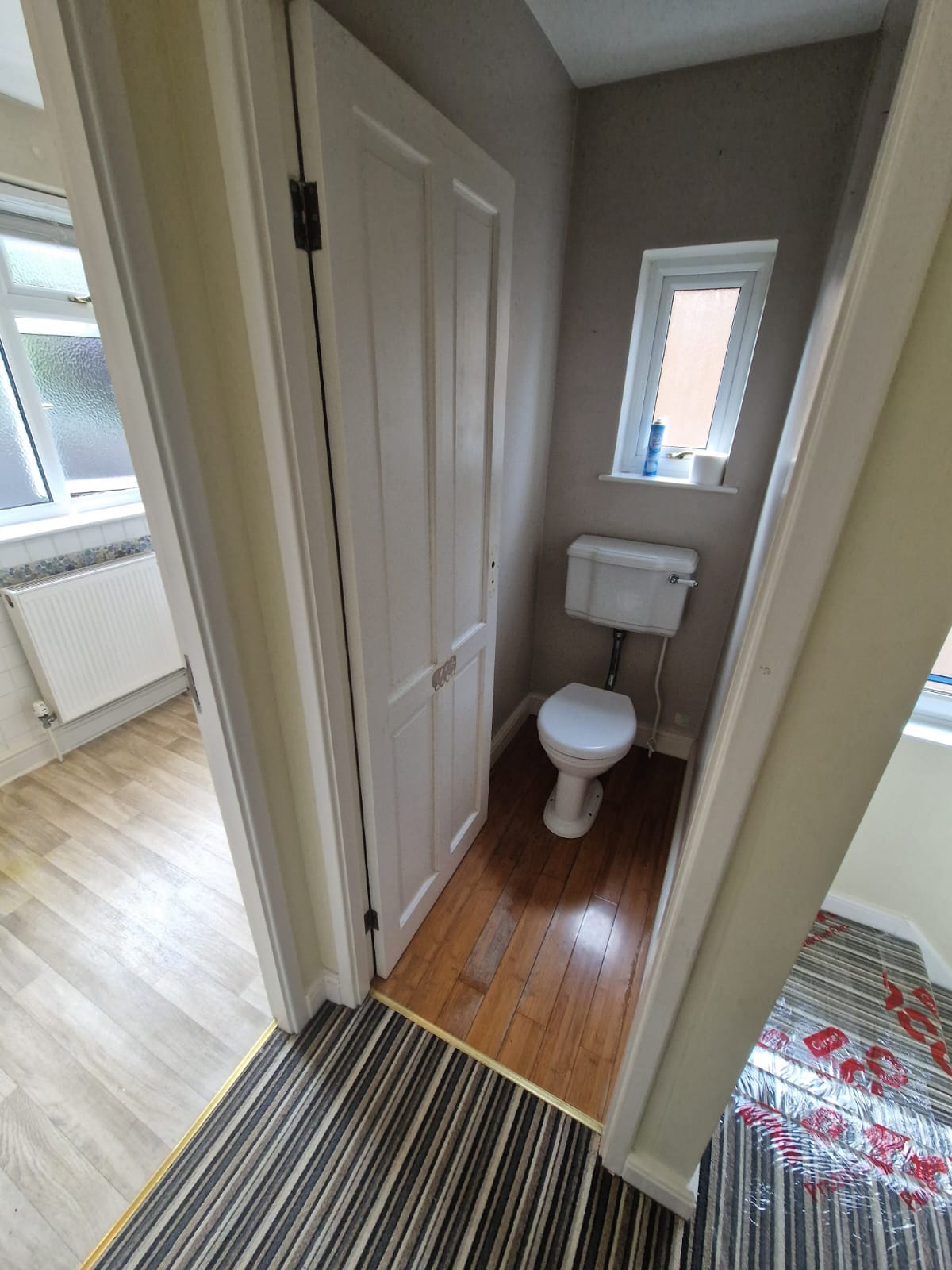 The separate WC before the work, with a low level cistern and varnished floorboards