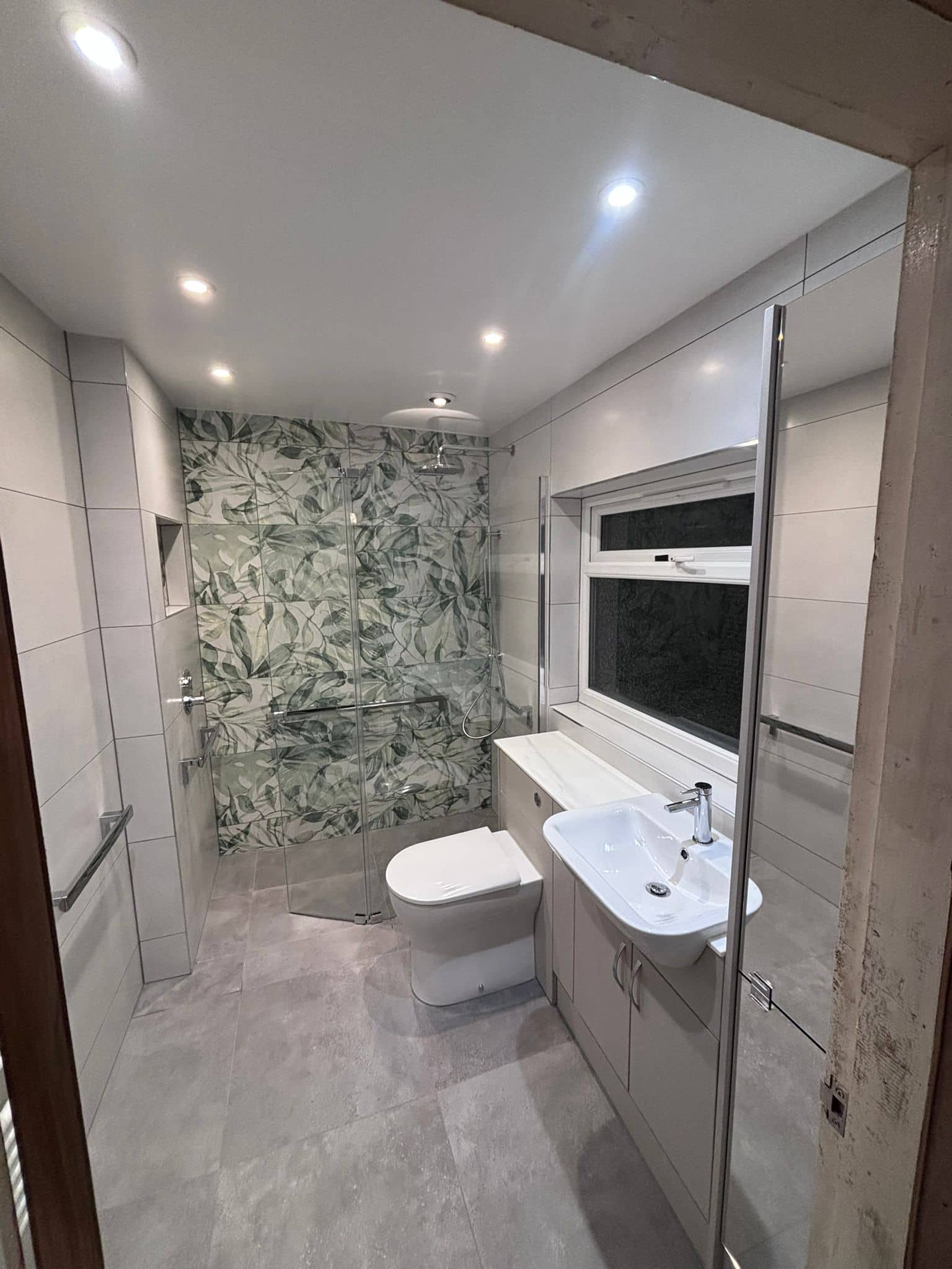 Level-access wet room with botanical feature tiles, glass screen and countertop basin