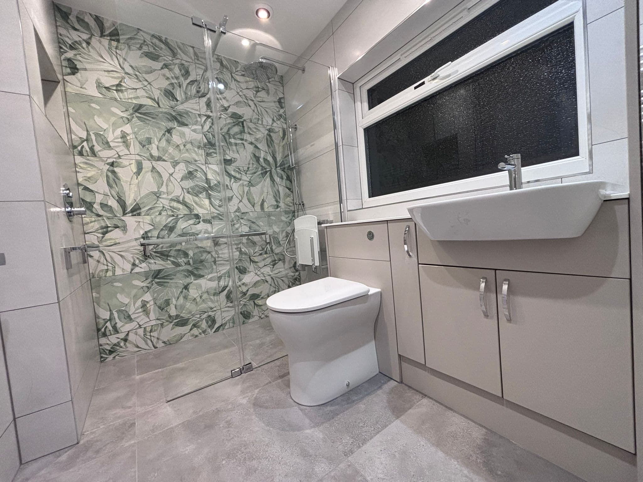 Open level-access wet room with glass screen, toilet and vanity