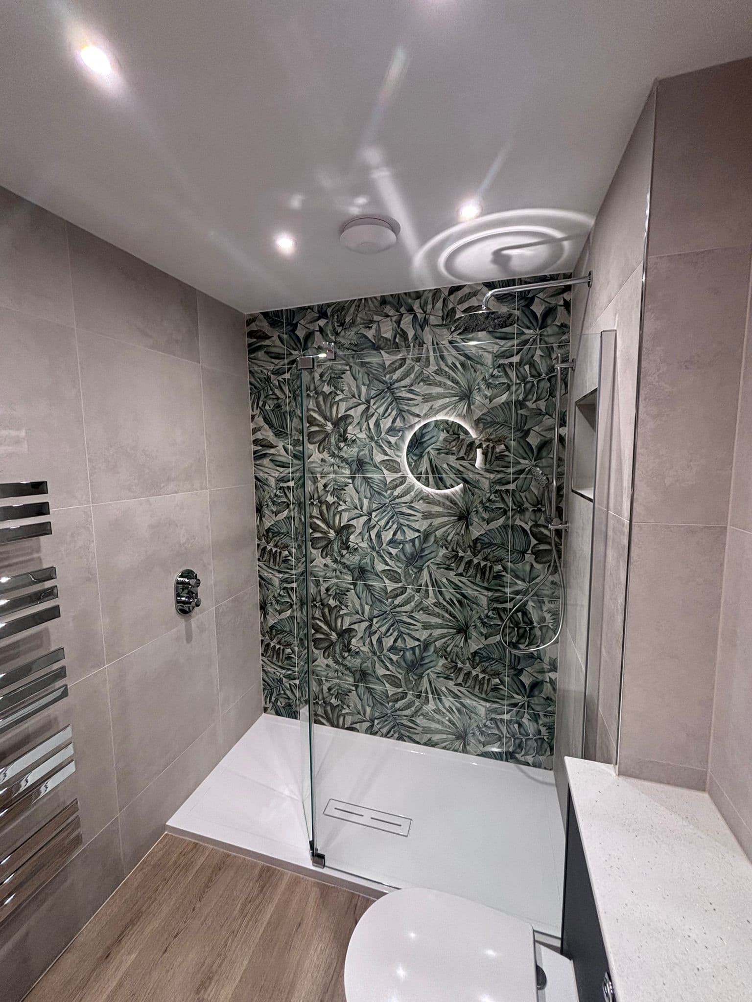 Green leaf feature tiles filling the shower wall beneath a rainfall head