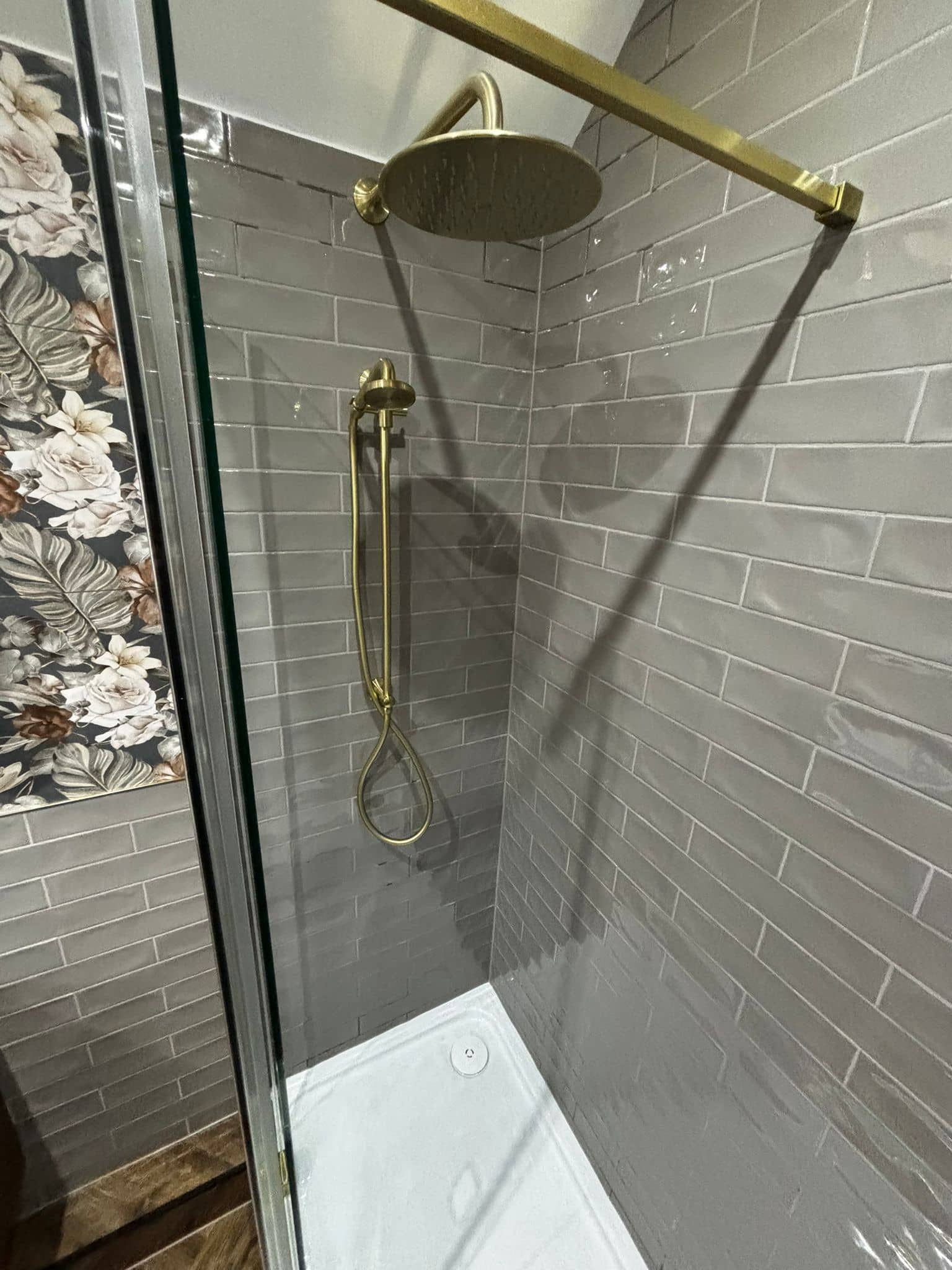 Gold rainfall shower against grey brick-effect tiles