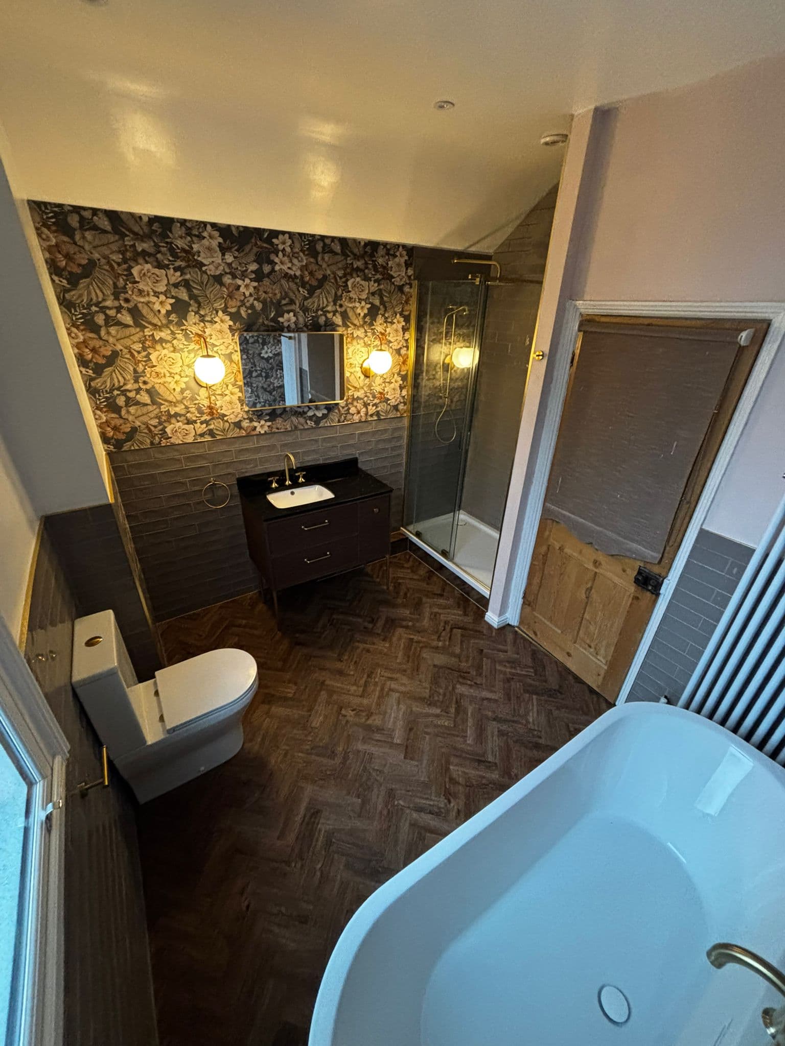 Full bathroom in warm evening light with freestanding bath, vanity and column radiator