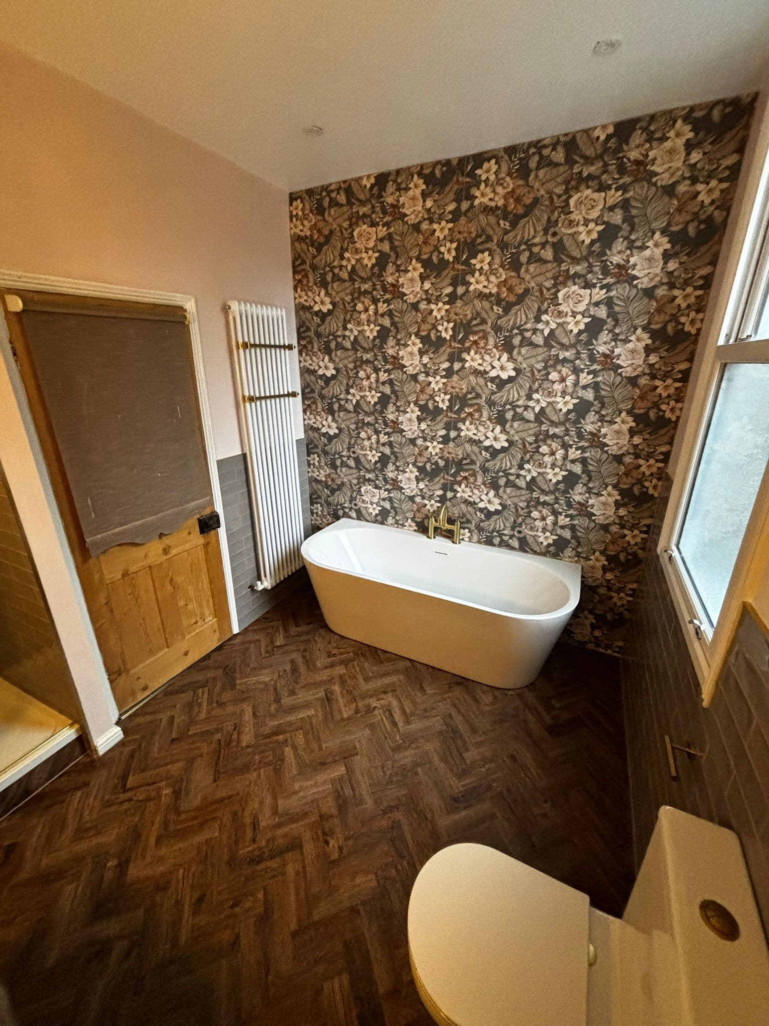 Freestanding bath and gold filler in front of a dark floral feature wall