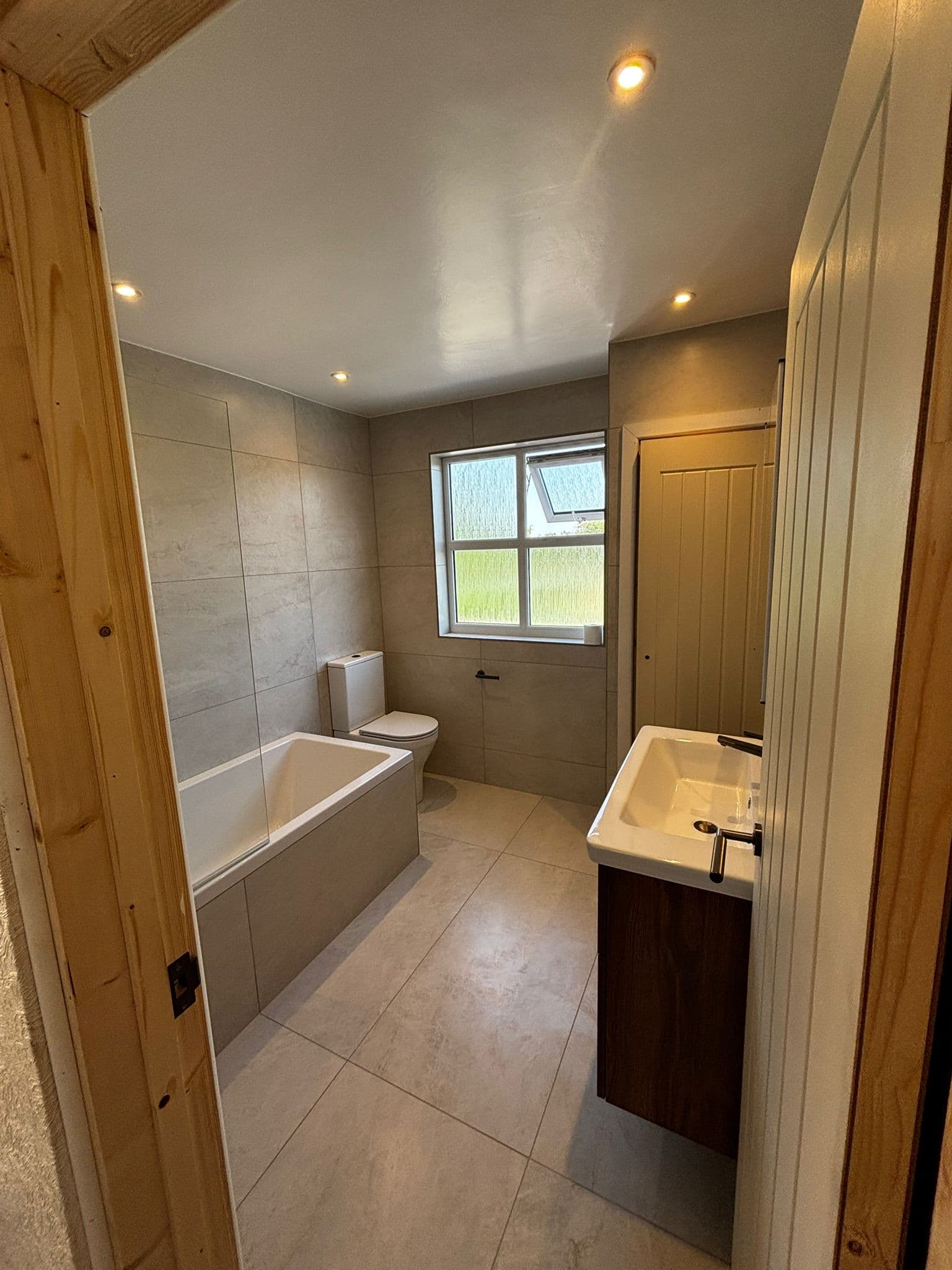 Family bathroom from the doorway with tiled bath panel, toilet and walnut vanity