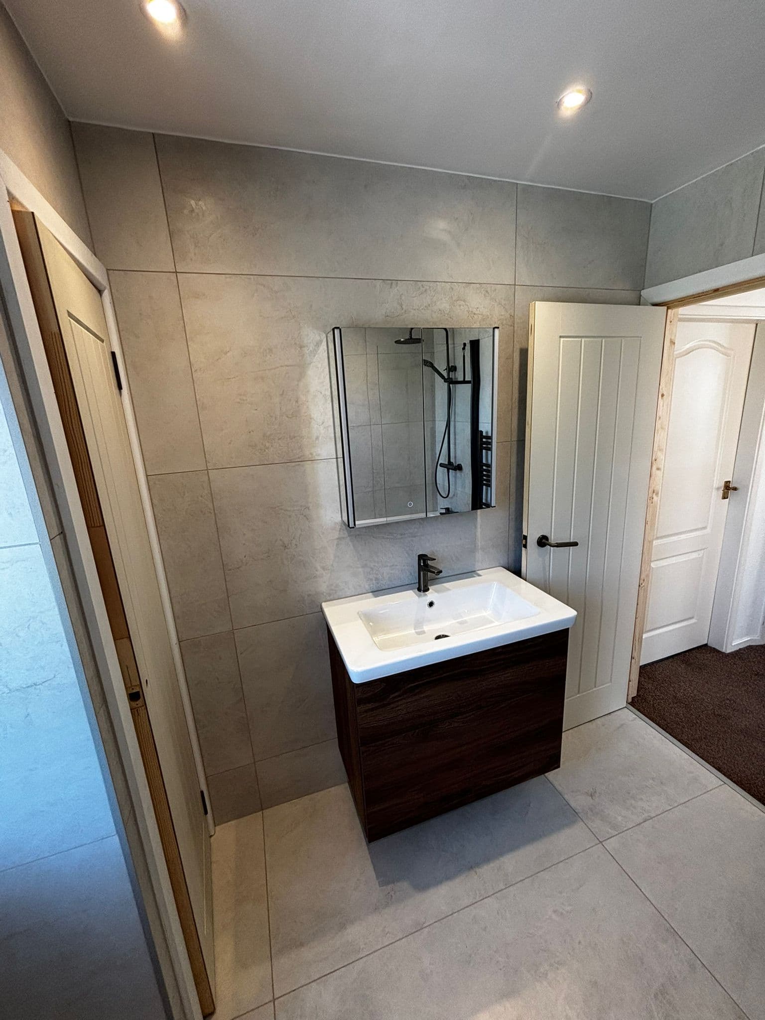 Backlit LED mirror cabinet over a walnut vanity with a matt black tap
