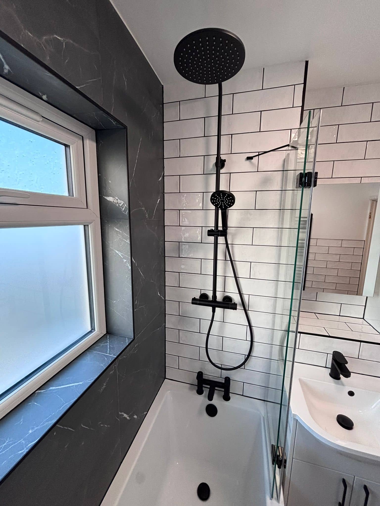 Matt black rainfall and hand shower against white metro tiles