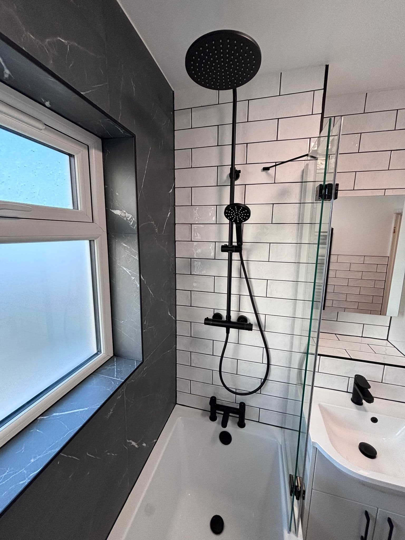 Matt black rainfall and hand shower against white metro tiles