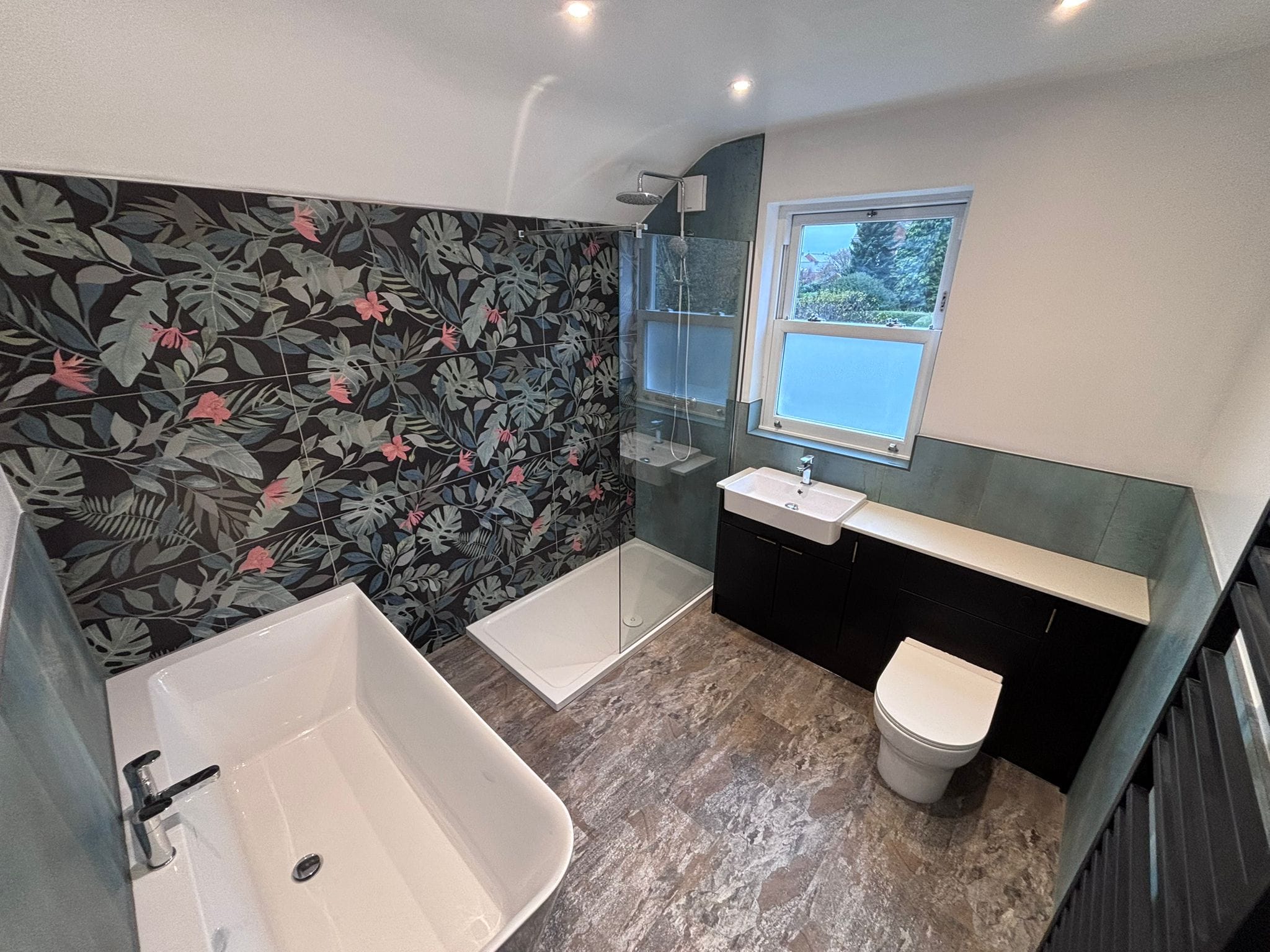 Loft en-suite with a freestanding bath, tropical feature wall and walk-in glass shower