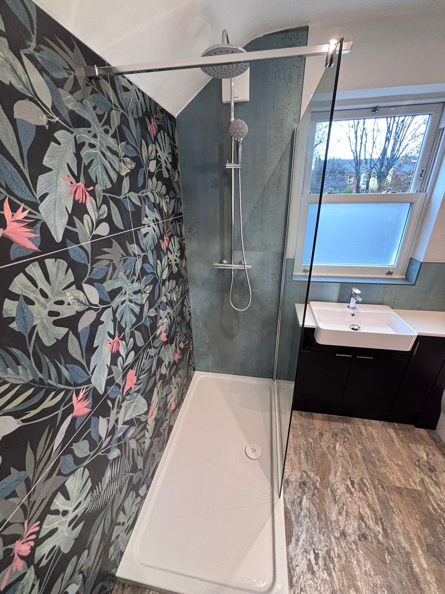 Chrome rainfall shower against a black and pink tropical feature wall