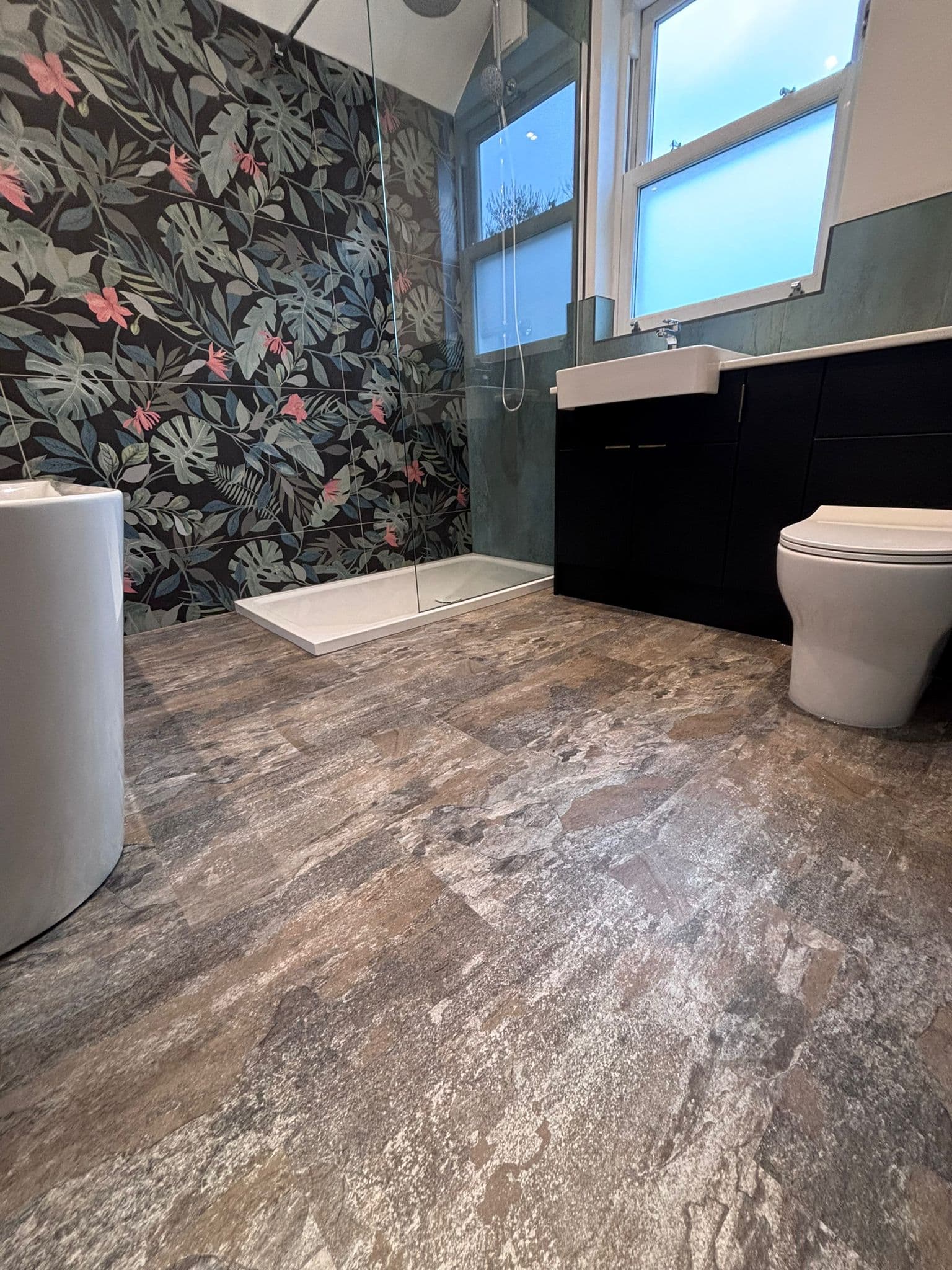 Full en-suite view with basin, tropical shower wall, dark vanity and toilet
