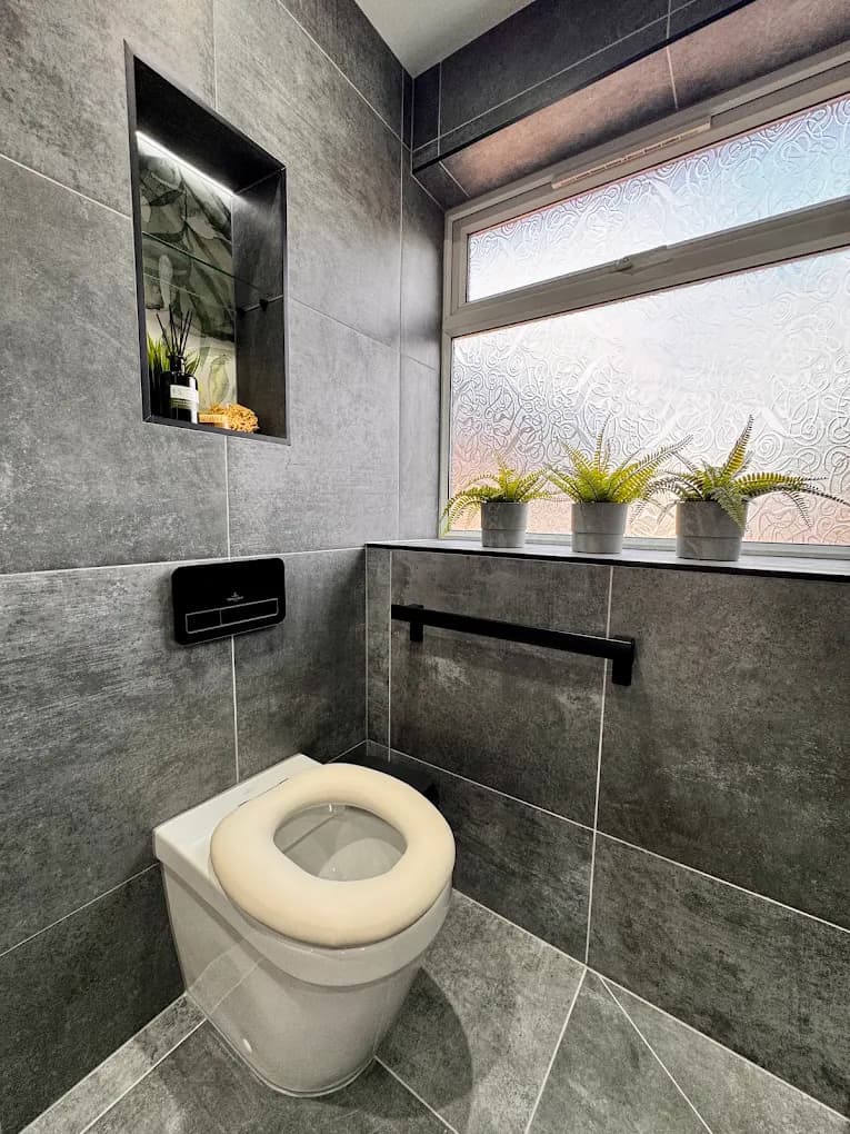 Cloakroom WC in grey marble-effect tile with trailing plants on the windowsill