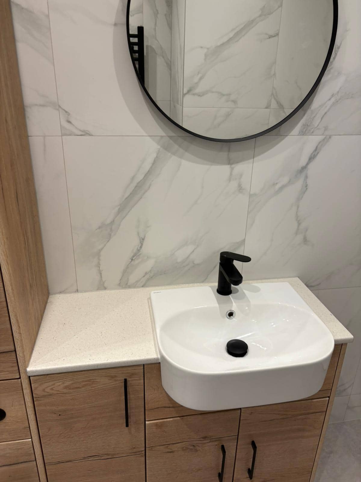 Oak-effect vanity with a stone worktop, semi-recessed basin and matt black tap, supplied by Goldswan