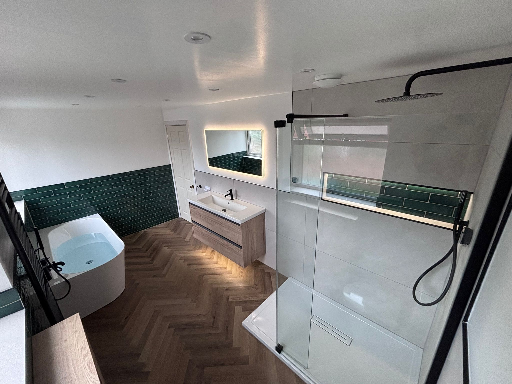 Finished bathroom with a freestanding bath, backlit vanity mirror and walk-in shower